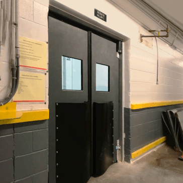 Traffic-Doors Double traffic door with a vision panel on each side, set in a cinderblock wall